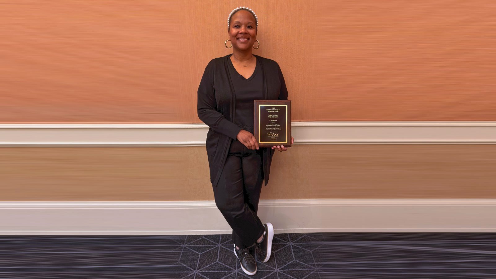 Dr. Nakia Best holding her 2026 National Academy of School Nursing Fellow plaque