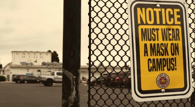 Mask requirement notice sign on a school fence in Santa Ana, Orange County
